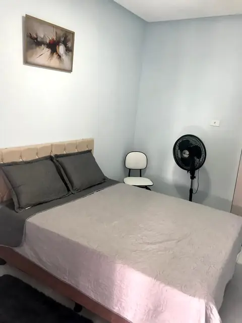 Quarto com cama de casal, ventilador e criado-mudo